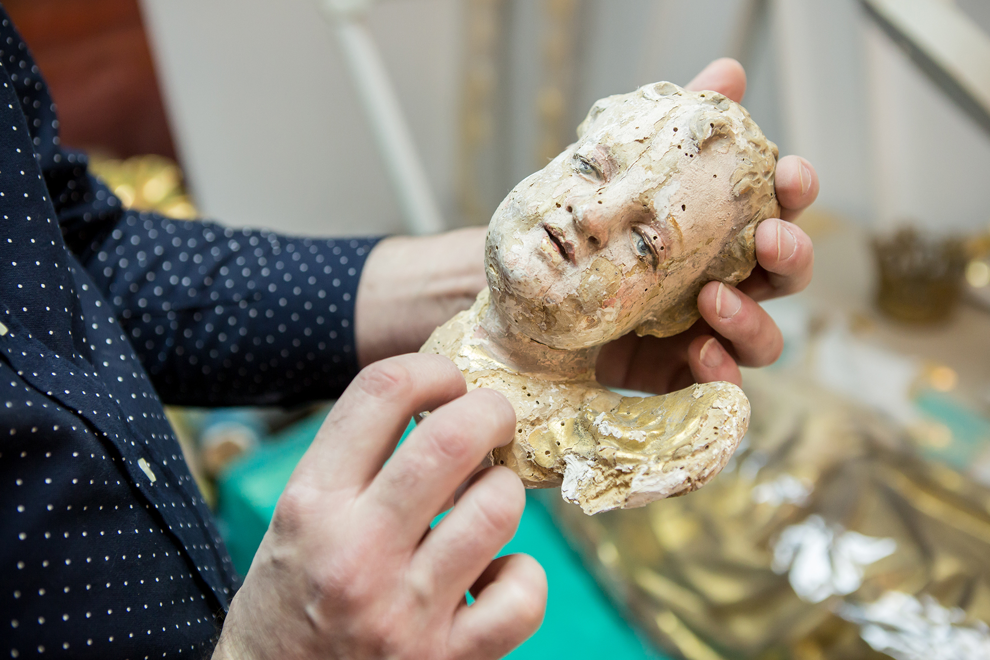 Bogdan pokazuje zniszczony motyw dekoracyjny przedstawiający głowę małego chłopca, tzw. putto.