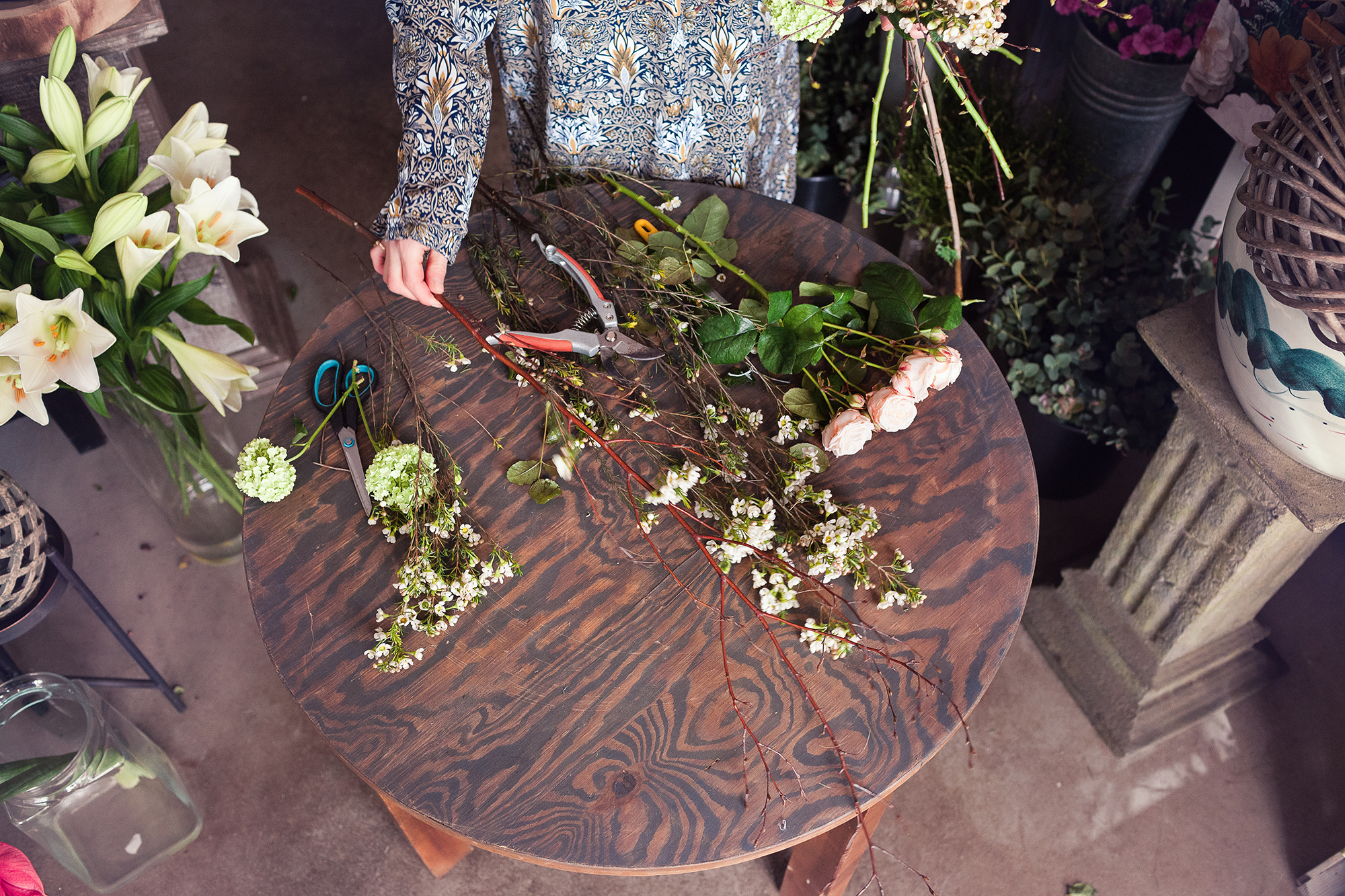 Stary drewniany stół a na nim potrzebne narzędzia do pracy w kwiaciarni. 
